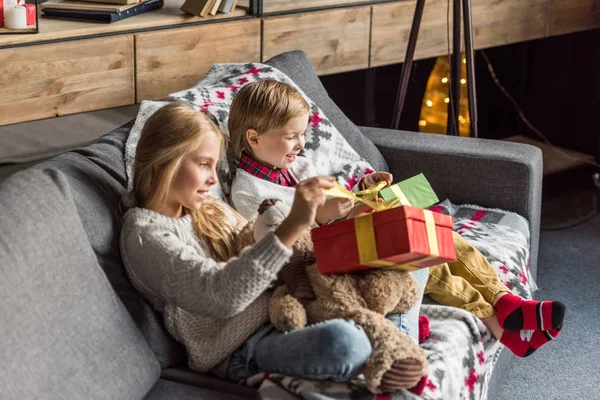 Vista de ángulo alto de lindos niños felices abriendo regalos de Navidad en casa - foto de stock