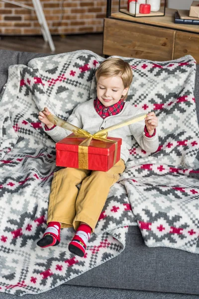 Blick aus der Vogelperspektive auf einen glücklichen kleinen Jungen, der zu Hause ein Weihnachtsgeschenk öffnet — Stockfoto