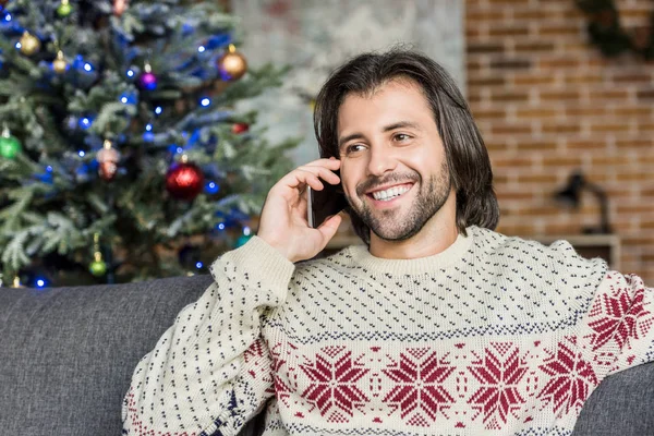 Bell'uomo sorridente che parla con lo smartphone e distoglie lo sguardo al periodo natalizio — Stock Photo