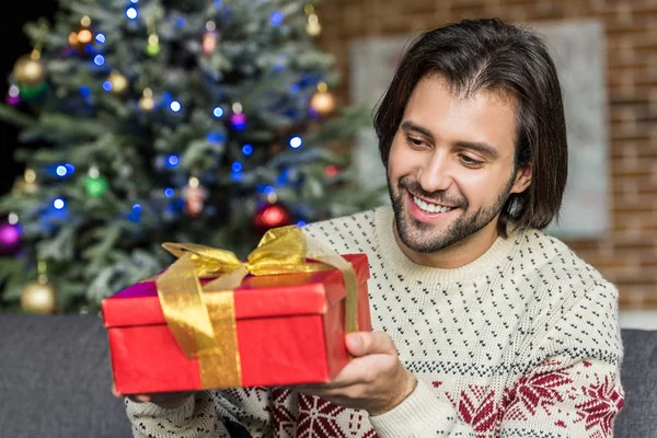Bonito feliz homem segurando Natal presente em casa — Fotografia de Stock