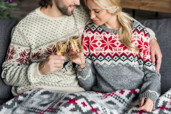 Cropped shot of happy young couple sitting together and drinking champagne at christmas time — Stock Photo