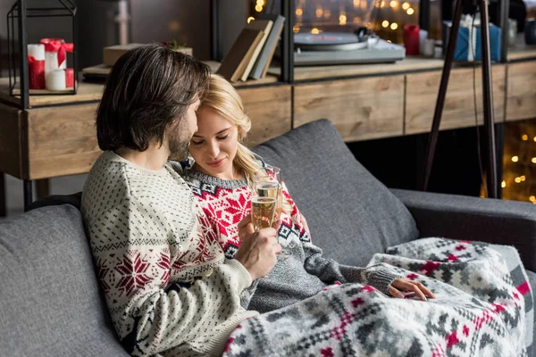 Feliz jovem casal sentado juntos e bebendo champanhe na época do Natal — Fotografia de Stock