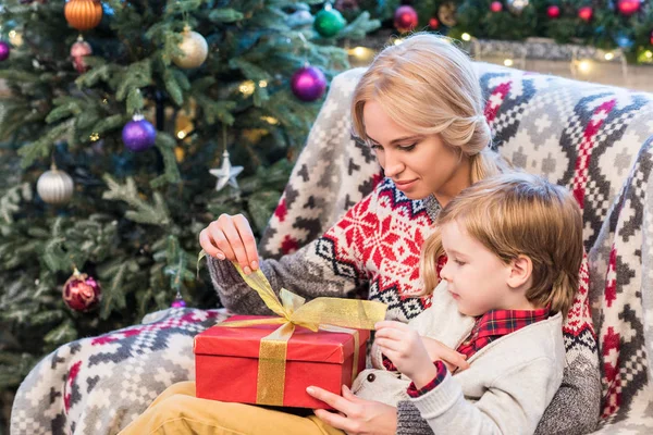 Young mother and cute little son opening christmas gift together — Stock Photo