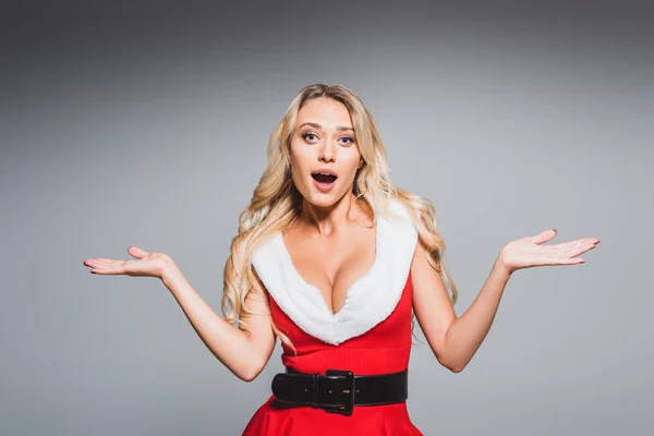 Surprised beautiful woman in santa dress doing shrug gesture isolated on grey background — Stock Photo