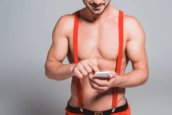 Partial view of sexy man in christmas hat using smartphone isolated on grey background — Stock Photo