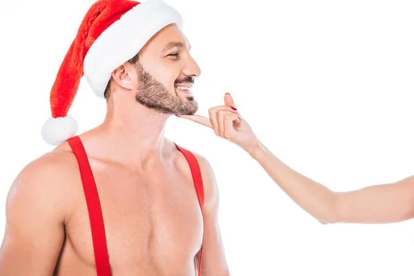Immagine ritagliata di donna che tocca mento del suo fidanzato muscoloso senza maglietta in cappello di Natale isolato su sfondo bianco — Foto stock