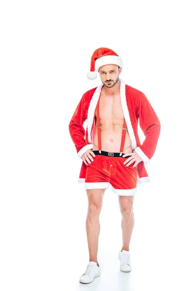 Giovane uomo muscoloso in costume da Babbo Natale e pantaloncini mostrando busto isolato su sfondo bianco — Foto stock