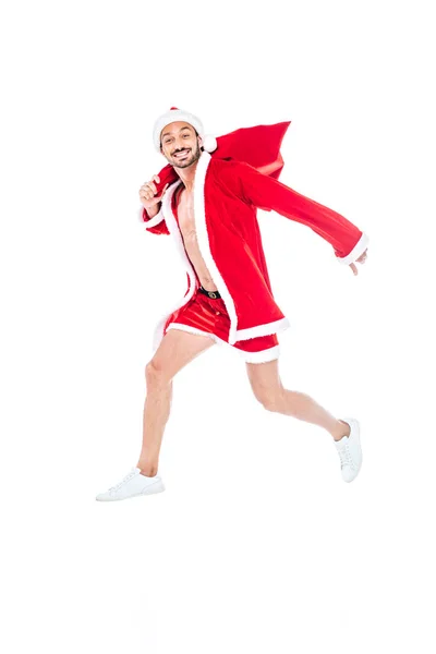 Happy muscular man in santa claus costume jumping with christmas sack isolated on white background — Stock Photo