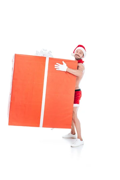 Hemdloser muskulöser Mann mit Weihnachtsmütze hält große Geschenkbox isoliert auf weißem Hintergrund — Stockfoto