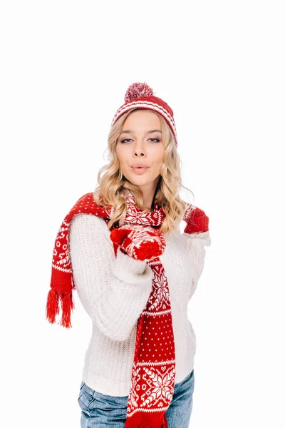 Красива молода жінка в капелюсі, шарфі і рукавицях дме поцілунок і дивиться на камеру ізольовано на білому — Stock Photo