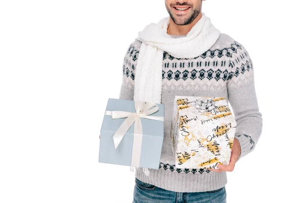 Tiro cortado de jovem sorridente em suéter e cachecol segurando caixas de presente isolado no branco — Fotografia de Stock