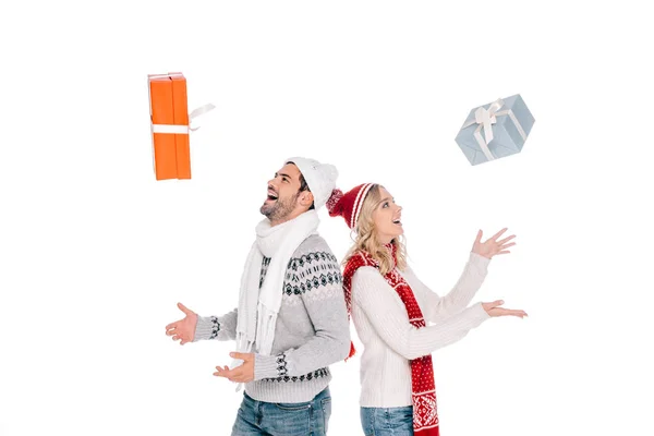 Vista lateral de feliz jovem casal de pé de volta para trás e jogando caixas de presente isolado no branco — Fotografia de Stock