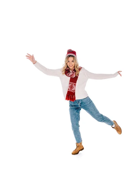 Vue pleine longueur de belle jeune femme heureuse en pull, écharpe et chapeau s'amuser et sourire à la caméra isolée sur blanc — Photo de stock