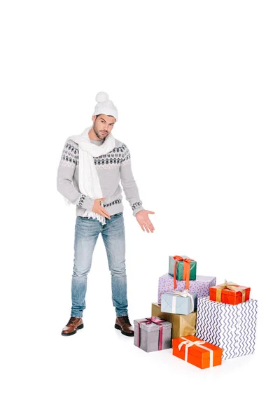 Schöner Mann in Schal und Mütze zeigt Geschenkboxen und blickt vereinzelt in die Kamera auf weiß — Stockfoto