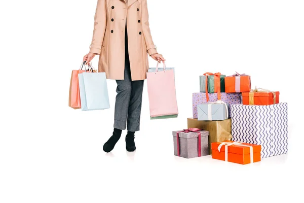 Plan recadré de femme tenant des sacs à provisions et debout près de boîtes-cadeaux isolées sur blanc — Photo de stock