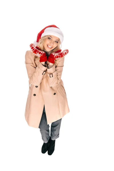 Vista ad alto angolo di bella giovane donna in cappello di Babbo Natale e guanti sorridenti alla fotocamera isolata su bianco — Foto stock