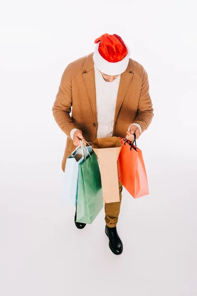 Високий кут зору людини в капелюсі Санта, що тримає сумки для покупок ізольовані на білому — стокове фото