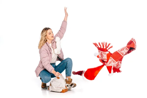 Young woman crouching with backpack and looking at red scarf isolated on white — Stock Photo