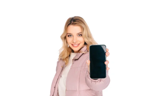 Junge Frau hält Smartphone mit leerem Bildschirm und lächelt in Kamera isoliert auf weiß — Stockfoto