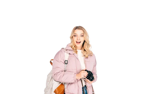 Beautiful excited young woman with backpack holding camera isolated on white — Stock Photo