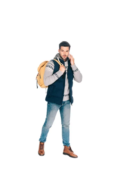 Schöner junger Mann mit Rucksack, der mit dem Smartphone spricht und isoliert auf die Kamera schaut — Stockfoto