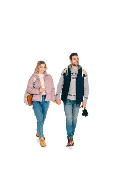 Vue pleine longueur de sourire jeune couple de touristes avec des sacs à dos tenant caméra et café pour aller isolé sur blanc — Stock Photo