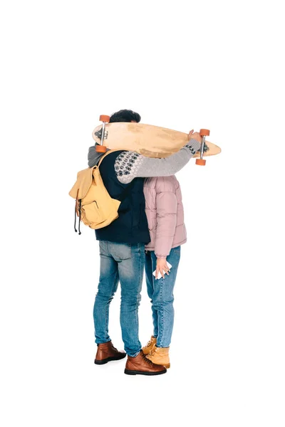 Vista completa de pareja joven escondiendo caras detrás de longboard aislado en blanco - foto de stock