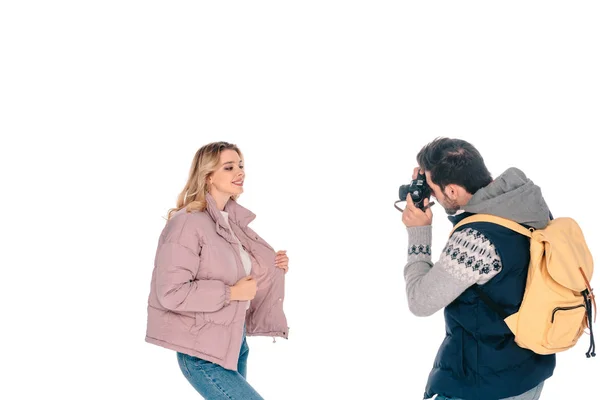 Homme avec sac à dos tenant la caméra et photographiant belle petite amie isolée sur blanc — Photo de stock