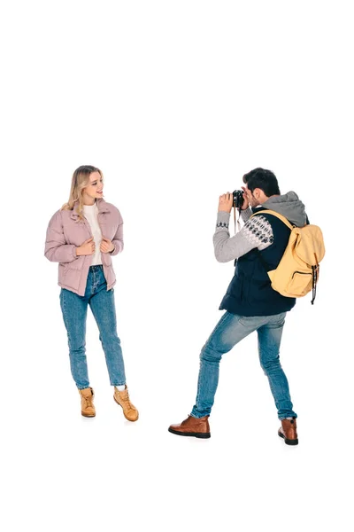 Volle Länge Ansicht des Mannes mit Rucksack hält Kamera und fotografiert schöne Freundin isoliert auf weiß — Stockfoto