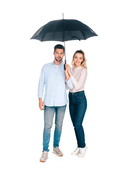 Full length view of beautiful happy young couple holding umbrella and smiling at camera isolated on white — Stock Photo