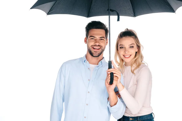 Beautiful happy young couple holding umbrella and smiling at camera isolated on white — Stock Photo