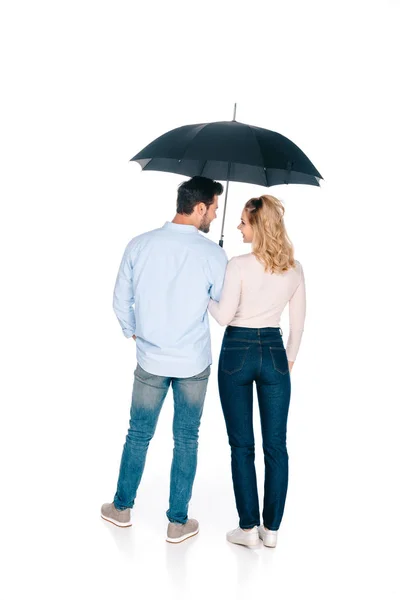 Visão traseira do jovem casal segurando guarda-chuva e sorrindo uns aos outros isolado no branco — Fotografia de Stock
