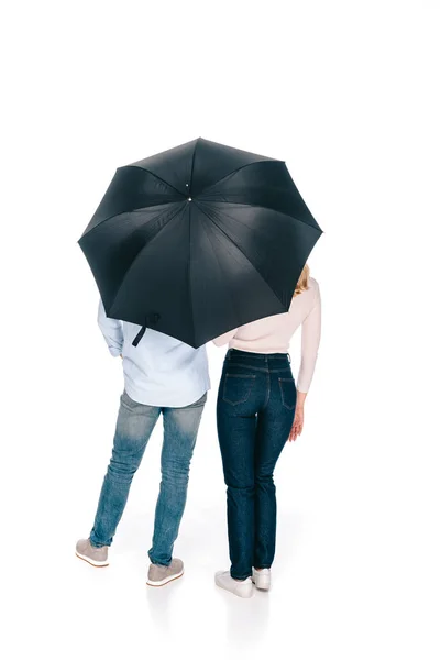 Vista posterior de la joven pareja de pie bajo el paraguas aislado en blanco - foto de stock