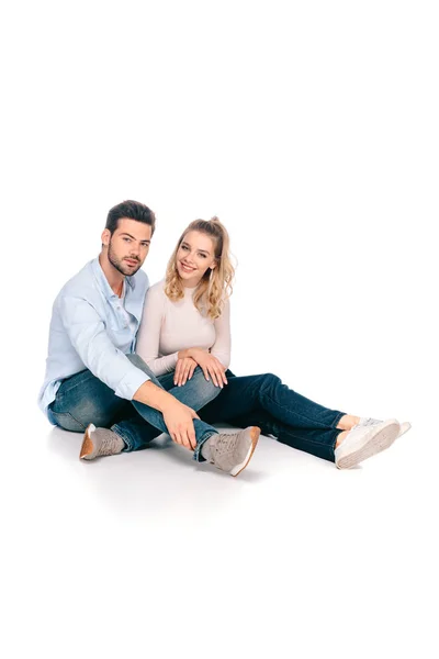 Feliz joven pareja sentado juntos y sonriendo a la cámara aislado en blanco - foto de stock