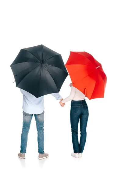 Vue de dos de jeune couple avec des parapluies noirs et rouges tenant les mains isolées sur blanc — Photo de stock