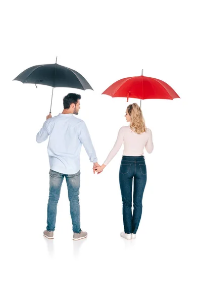 Vista trasera de pareja joven con paraguas tomados de la mano y mirándose aislados en blanco - foto de stock