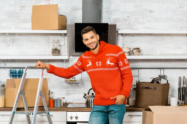 Fröhlicher junger Mann steht neben Leiter in Küche im neuen Heim — Stockfoto