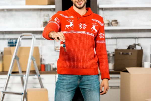 Частковий вигляд молодого чоловіка, що показує ключі на кухні з картонними коробками під час переміщення в новому будинку — стокове фото