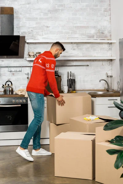 Rear view of man taking cardboard box in kitchen during relocation at new home — Stock Photo