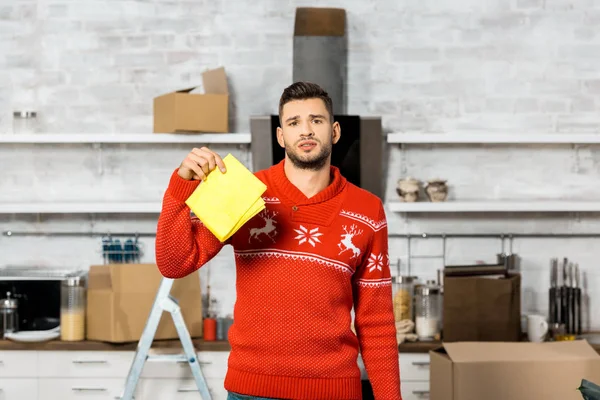 Emotional young man holding yellow dirty rag in kitchen during relocation at new home — Stock Photo