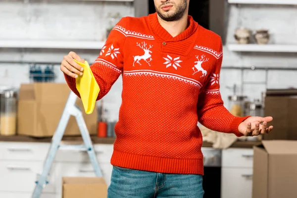 Young man holding yellow dirty rag and doing shrug gesture in kitchen during relocation at new home — Stock Photo