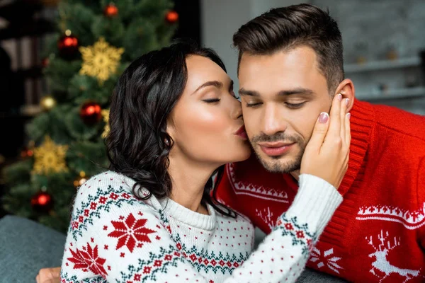 Foyer sélectif de jeune femme embrassant petit ami près de l'arbre de Noël à la maison — Photo de stock