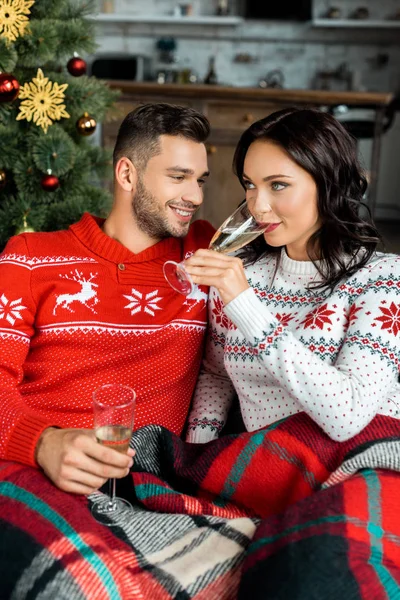 Selektiver Fokus des Paares, das mit Champagnergläsern auf dem Sofa neben dem Weihnachtsbaum zu Hause schläft — Stockfoto