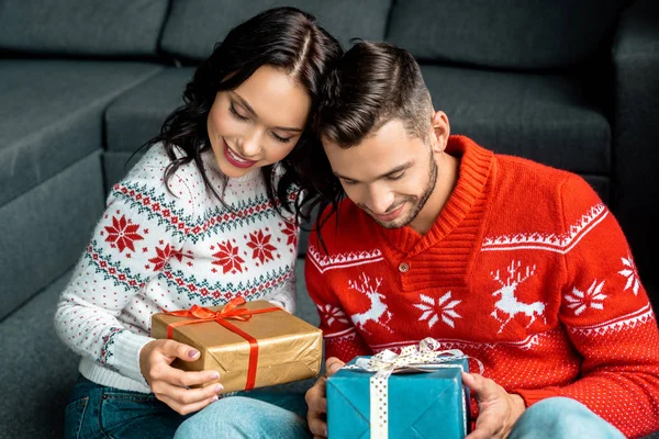 Selective focus of happy couple sitting with christmas gift boxes at home — Stock Photo