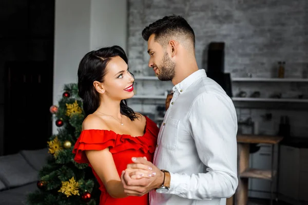 Side view of happy young couple looking at each other and dancing on christmas at home — Stock Photo