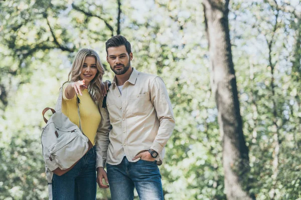 Portrait de jeune couple amoureux dans le parc, fille pointant vers vous — Photo de stock