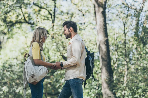 Vista laterale della giovane coppia innamorata che si tiene per mano nel parco — Foto stock