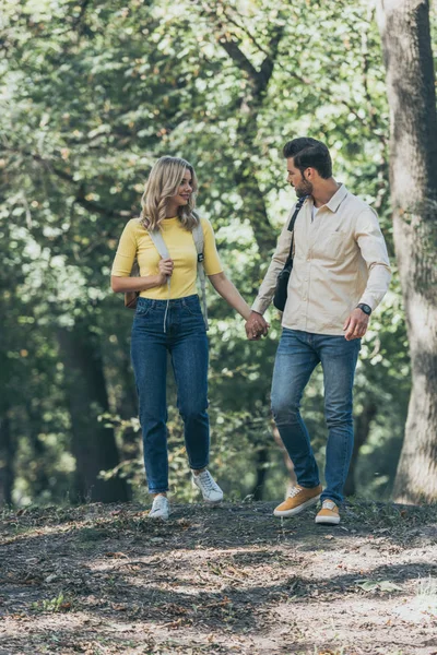 Young couple holding hands while walking in autumn park together — Stock Photo