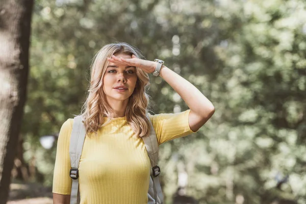 Porträt einer schönen jungen Frau mit Rucksack, die im Park wegschaut — Stockfoto