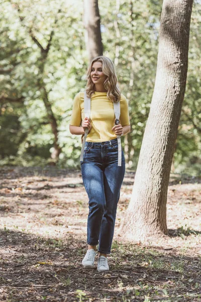 Schöne junge Frau mit Rucksack zu Fuß in Park — Stockfoto